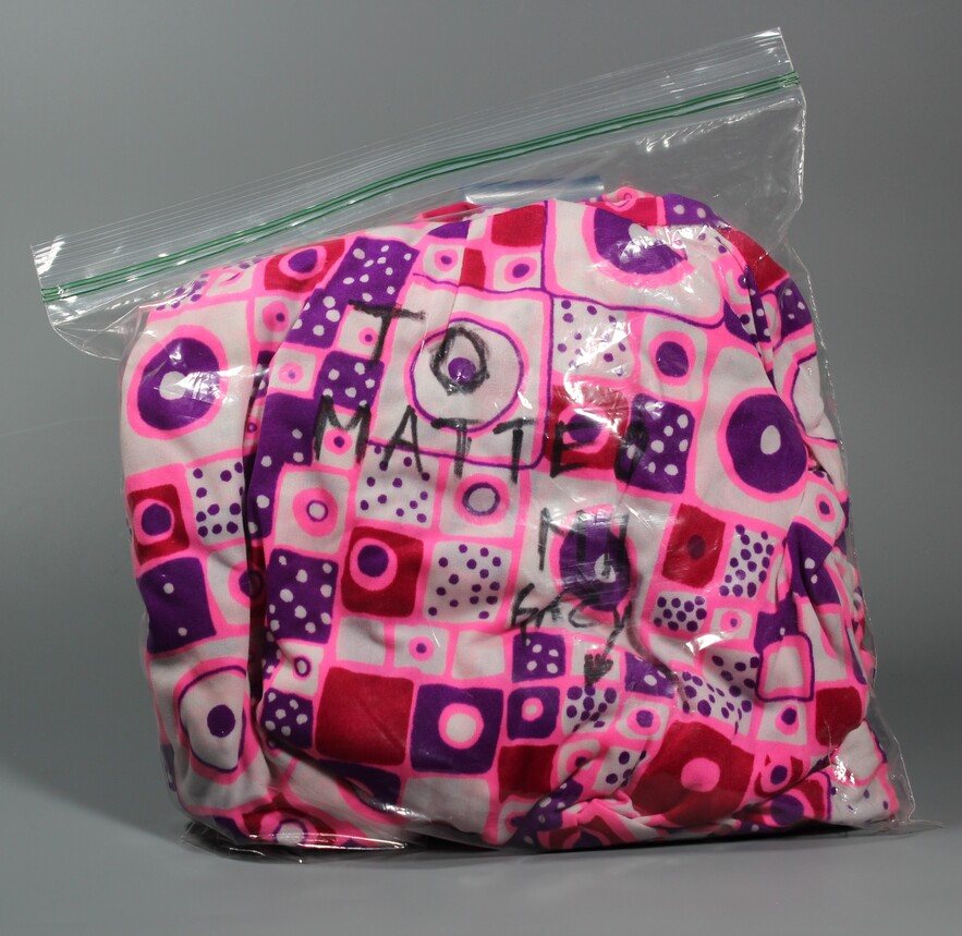 Dress preserved in a protective bag, with the handwritten dedication “To Matteo, MW Gacy” visible on the fabric.